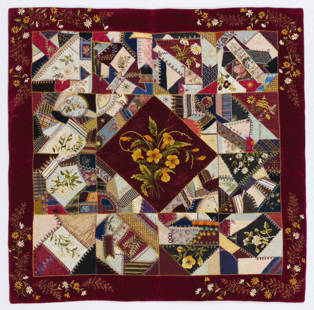 Image features: Patchwork cover made from a variety of woven fabrics and ribbons. Diamond shape in the center with a triangle on each side to form a central square surrounded by twelve squares plus an outer border. Each square contains an embroidered naturalistic flower. Please scroll down to read the blog post about this object.”