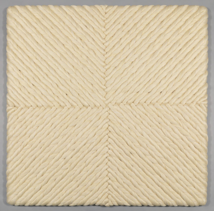 The natural linen woven base cloth is stretched in tension on a wooden frame. Skeins or coils of bleached linen are alternately twisted in the 's' or 'z' directions, and anchored to the foundation by sewing them with strong linen thread using a semi-circular needle, allowing the artist to control and stabilize the volume.