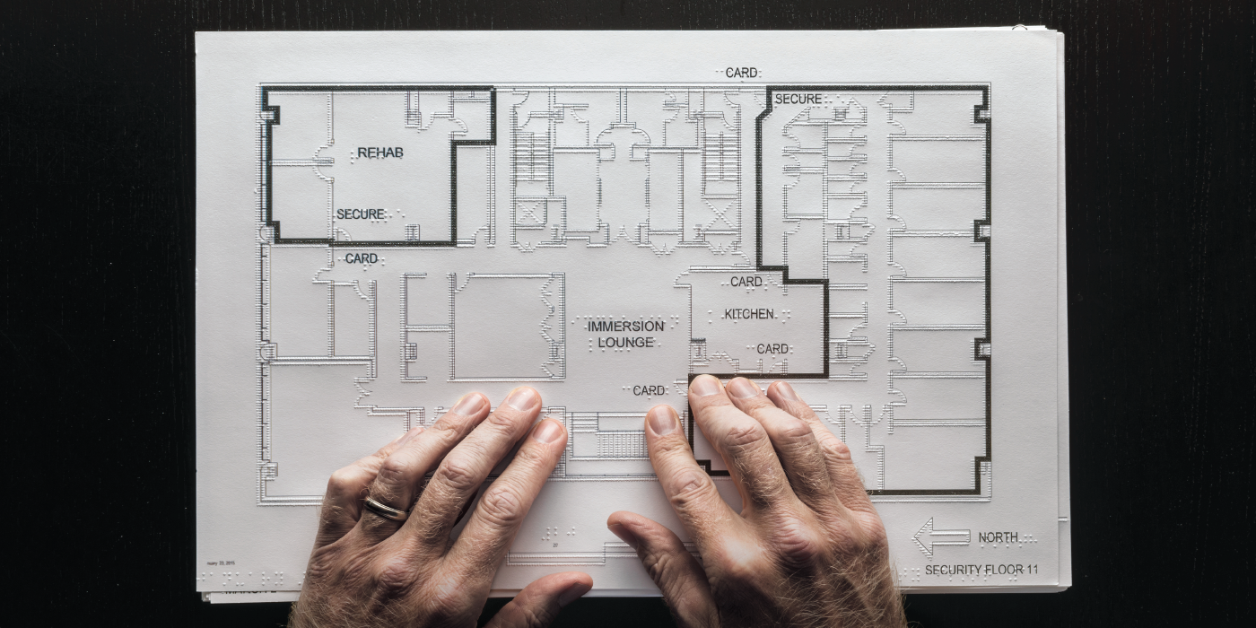 Photograph of tactile map with hands feeling raised image.