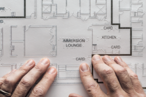Fingers explore a tactile architectural drawing.