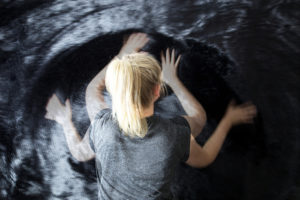 A woman stroking a large black furry wall, an installation on view in the exhibition The Senses: Design Beyond Vision. Scroll down to read more about the exhibition
