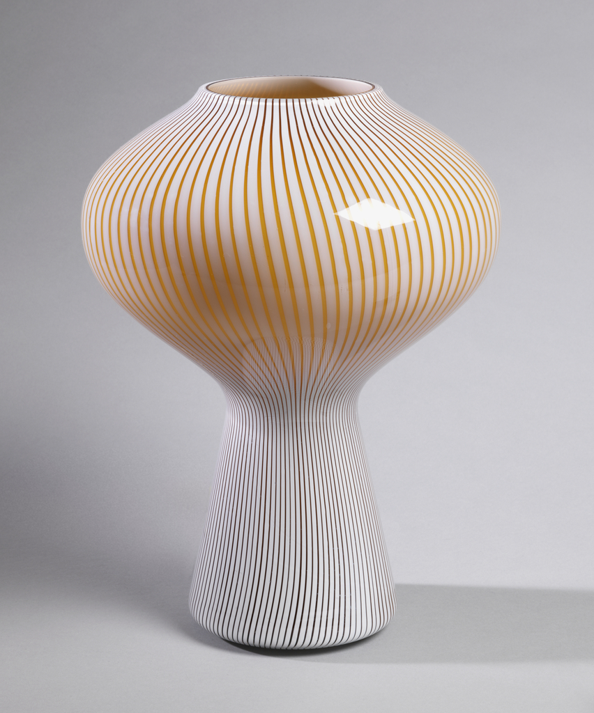 Image features one-piece table lamp consisting of a bulbous cap and tapering stem, its body made of alternating white and orange-brown vertically striped glass. Please scroll down to read the blog post about this object.