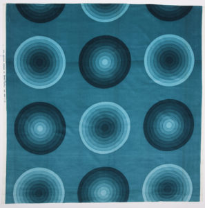 Printed velvet fabric with large bulls-eye circles in a gradation of turquoise shades.