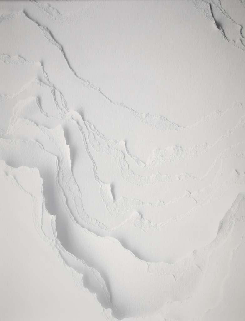 The image is a detail shot of a monochrome white wallpaper composed of torn and layered strips of paper. Please scroll down for a further description of this piece.