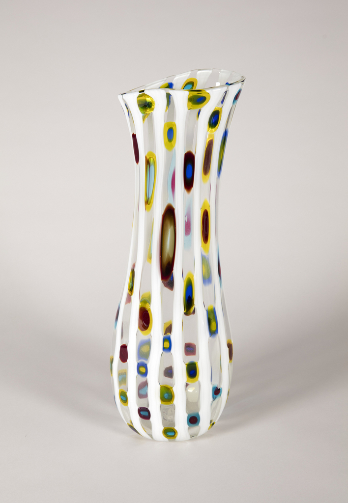 Image features tall vase with vertical rods of lattimo glass alternating with transparent glass containing irregular circular and oval polychromed murrine. Please scroll down to read the blog post about this object.