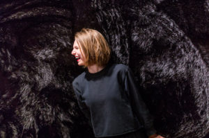 A woman leans against and strokes a wall covered in black fur in the exhibition The Senses: Design Beyond Vision, now on view. Scroll down for information about a verbal description and sensory tour of the exhibit.