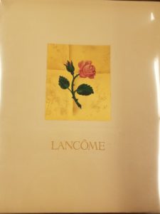 Image features pink rose on gold fly with gold lettering titled Lancôme. Please scroll down to read the blog post about this object.