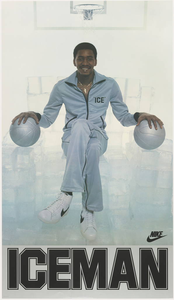 Image features photograph of George “The Iceman” Gervin in a space filled with large ice cubes, holding a silver basketball in each hand, wearing a silver tracksuit with the word: ‘ICE’ embroidered on the chest. He wears white Nike sneakers. In lower margin: ICEMAN; lower left of photograph: NIKE logo. Please scroll down to read the blog post about this object.