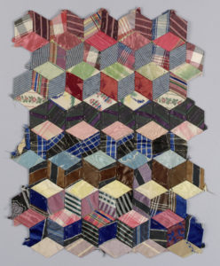 Image features fragment of a quilt top in "Tumbling Blocks" pattern, made from small diamond shapes stitched together to create the illusion of cubes. The woven pieces are in silk stripes, plaids and a few small floral patterns. Please scroll down to read the blog post about this object.
