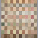 Small-scale rectangular weaving with a checkerboard pattern of squares in soft shades of brown, tan, green, and pink.