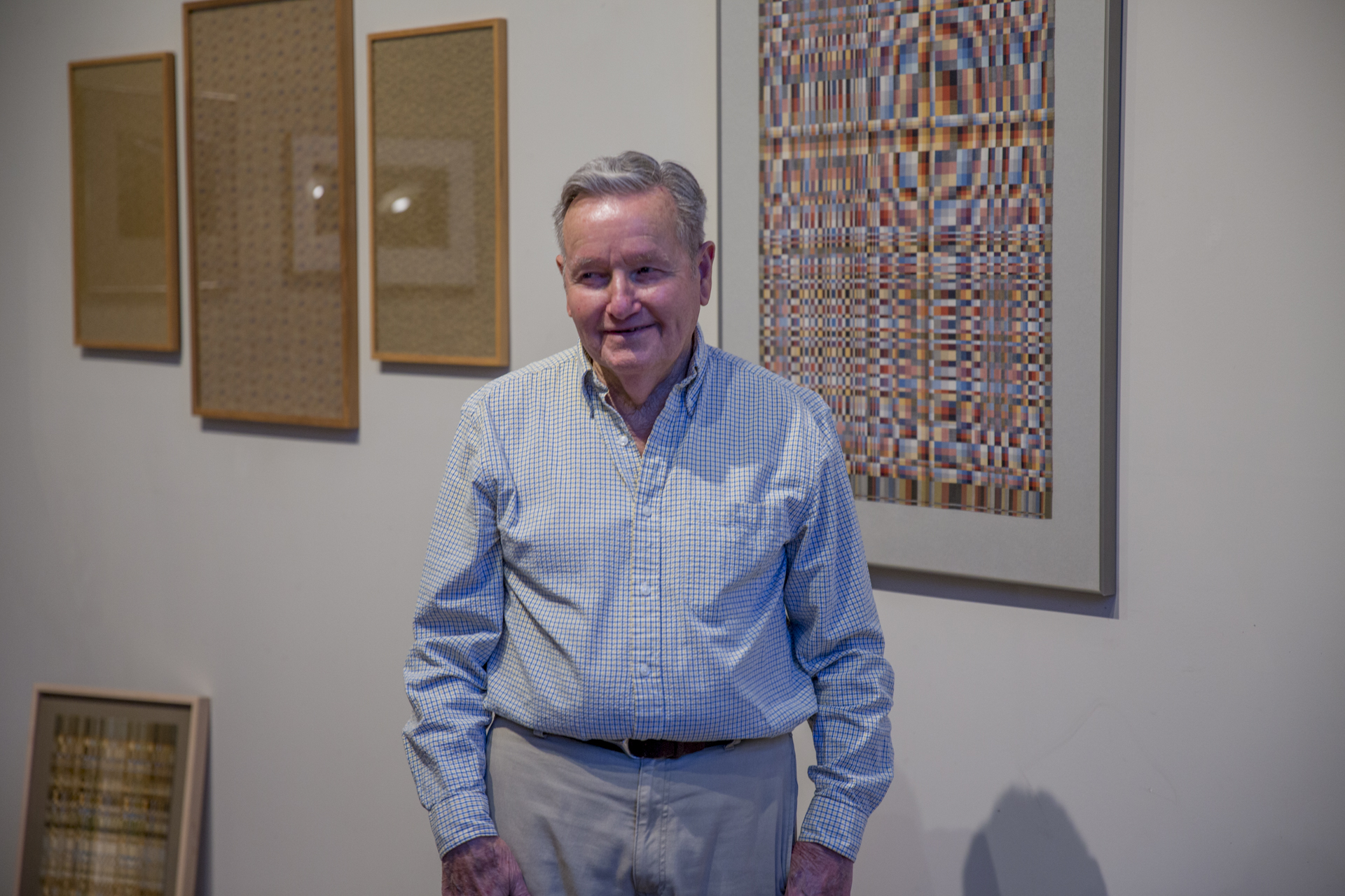Image of Richard Landis, a silver haired man wearing a white and blue checkered shirt, in his studio.