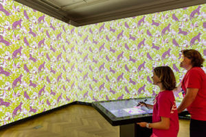 A mother and daughter explore wallpaper design in the museum's Immersion Room, a creative tech experience.
