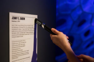 A visitor presses the Cooper Hewitt Pen to an object label to activate the Pen to save the object information for the visitor to access online.