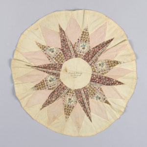 Image features patchwork medallion with a star pattern in unbleached cotton and three roller-printed cottons in browns, tans and pinks. Handwritten in dark brown ink in the center circle: "Olivia C. Whitridge, New Bedford, 1853." Please scroll down to read the blog post about this object.