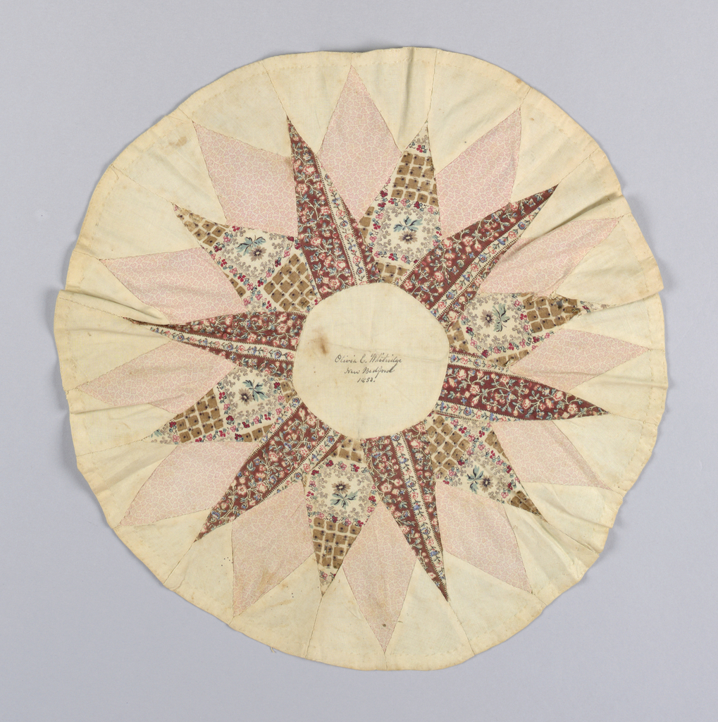 Image features patchwork medallion with a star pattern in unbleached cotton and three roller-printed cottons in browns, tans and pinks. Handwritten in dark brown ink in the center circle: "Olivia C. Whitridge, New Bedford, 1853." Please scroll down to read the blog post about this object.