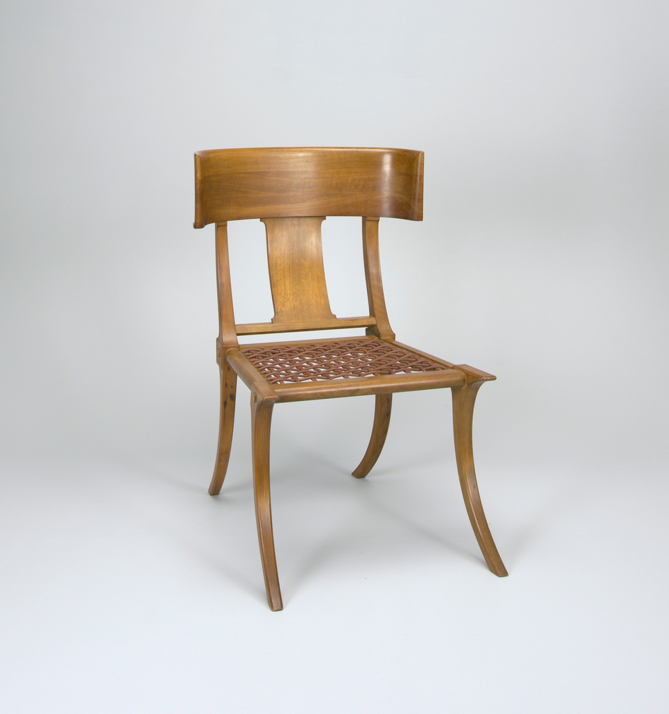 Image features walnut wood chair composed of concave backrest supported by two vertical curved rails flanking curved center splat; square webbed leather seat supported on splayed, tapering legs. Please scroll down to read the blog post about this object.