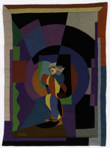 Image features: Rectangular hanging showing an abstracted figure of a man in profile. Border of long overlapping rectangles. Cut and stitched from wool felt in a wide range of brilliant colors, brown, black and gray. Signature "Fillia" in lower right corner in black thread stem stitch. In lower left corner "S.I.R.E." in yellow stem stitch. Please scroll down to read the blog post about this object.