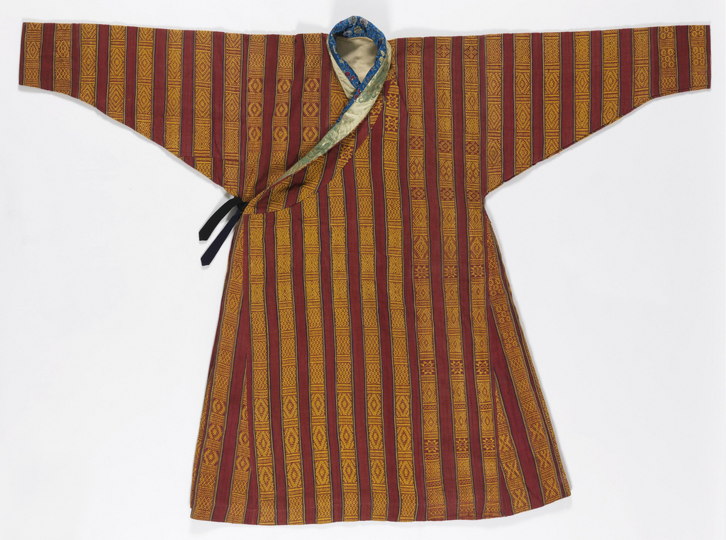 Hand-woven red wild silk robe with vertical stripes of supplementary warp patterning of small geometric motifs in golden yellow, banded by narrow stripes of blue, yellow, and green. Neck bands made of two Chinese brocaded silks, one blue with flowers and the other gold with dragons. Lined with heavy off-white twill. Black tie at side. The robe is gored to produce fullness, with a standing collar and asymmetrical closure. The set-in sleeves are very wide at the shoulder and taper sharply to the wrist, which is worn turned back. The robe is worn looped up at waist and gathered tightly at back, which produces a pouch-like area, at front.