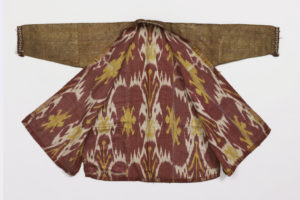 Image features a robe of gold metallic cloth with foundation fabric of terra-cotta silk. Edges trimmed with knitted silk in red, blue, yellow, black and white. Lined with silk and cotton ikat fabric in red, white and yellow. Please scroll down to read the blog post about this object.