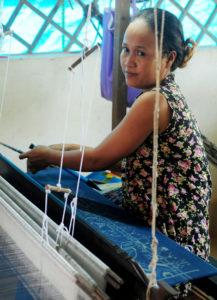 Young woman sitting at a loom.