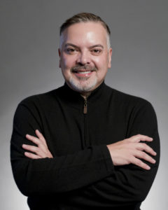 Image of Henry Munoz, man wearing a black sweater smiling and facing camera.