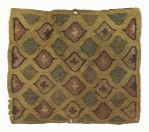 Tapestry-woven square with a geometric lozenge pattern in gold, pink, and green, with small crosses in black and white.