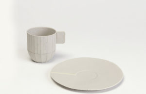 a pale grey espresso cup with a square handle and scored with vertical lines to reference a cardboard prototype, plus saucer, designed by Scholten & Baijings and now on view in Scholten & Baijings: Lessons from the Studio. Click on the image for more information about the installation.