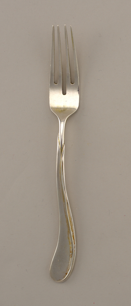 Image features a four-tined silver dessert fork, its form suggesting a tulip on its sinuous, leaf-encased stem. Please scroll down to read the blog post about this object.