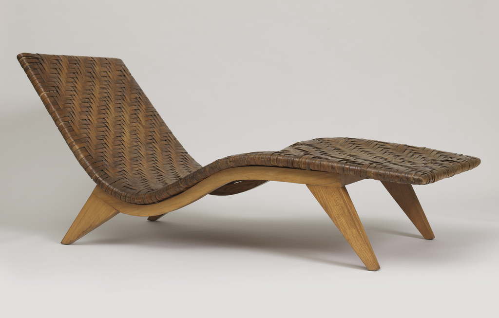 Image features chaise in the form of a long, contoured, rectangular seat/back unit of woven strips on curved wood frame with four flat, angled and tapered legs. Please scroll down to read the blog post about this object.