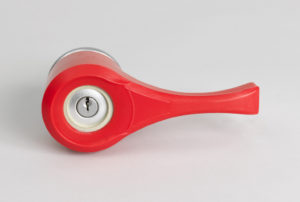 Image features red plastic form, circular opening at one side to fit over a door knob, tapering to long handle as hand grip to turn knob. Please scroll down to read the blog post about this object.