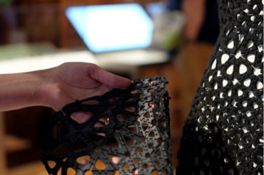 Close-up image of a hand holding a black plastic 3-D printed geometric material sample.