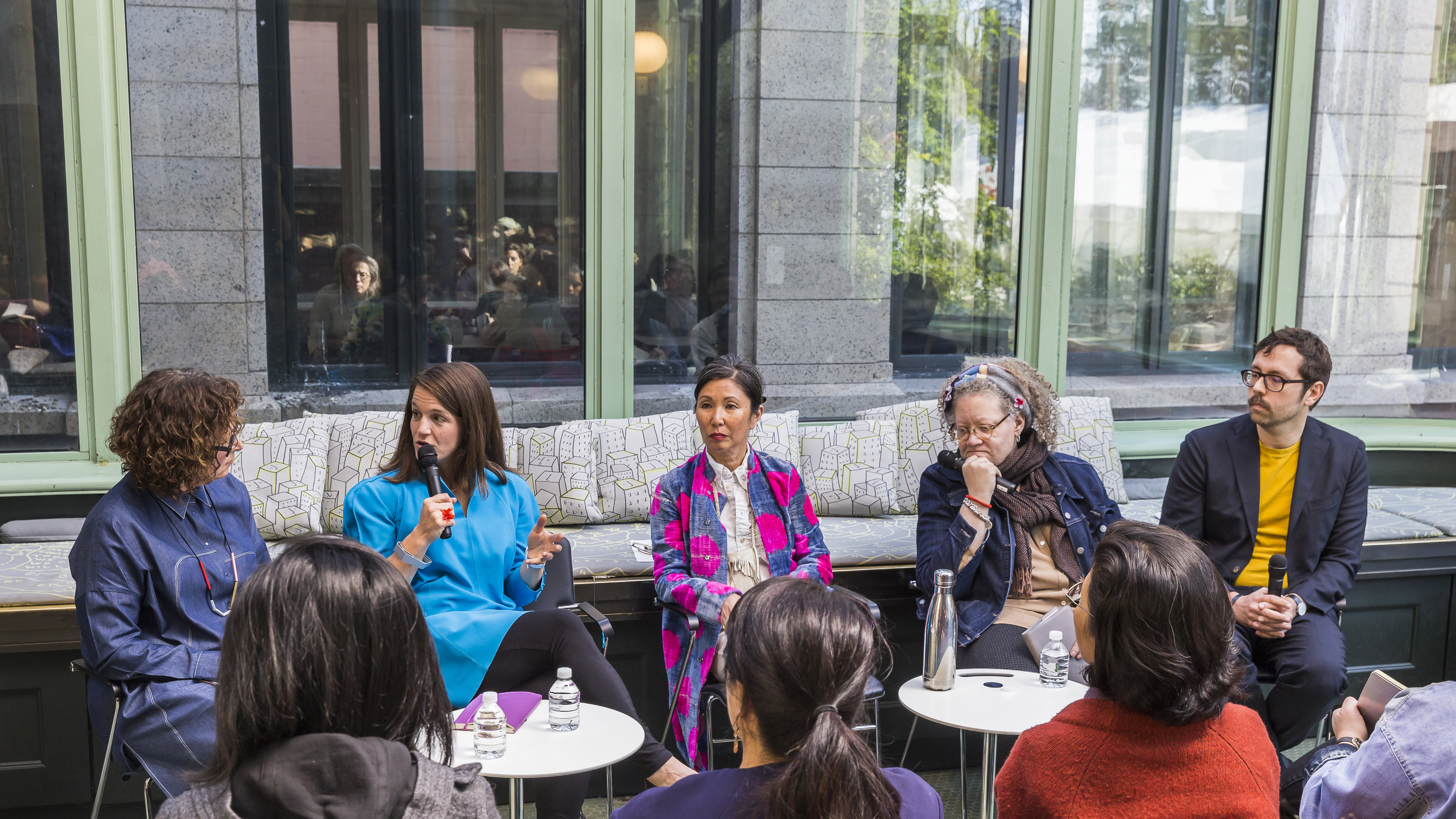 Image of a panel discussion in the Cooper Hewitt conservatory. From left to right: Cynthia Smith, curator in dark blue, Liz Gerber in bright blue, Christina Kim in pink and blue flower suit, Gail Anderson, in dark blue, and Gabriel Stromberg