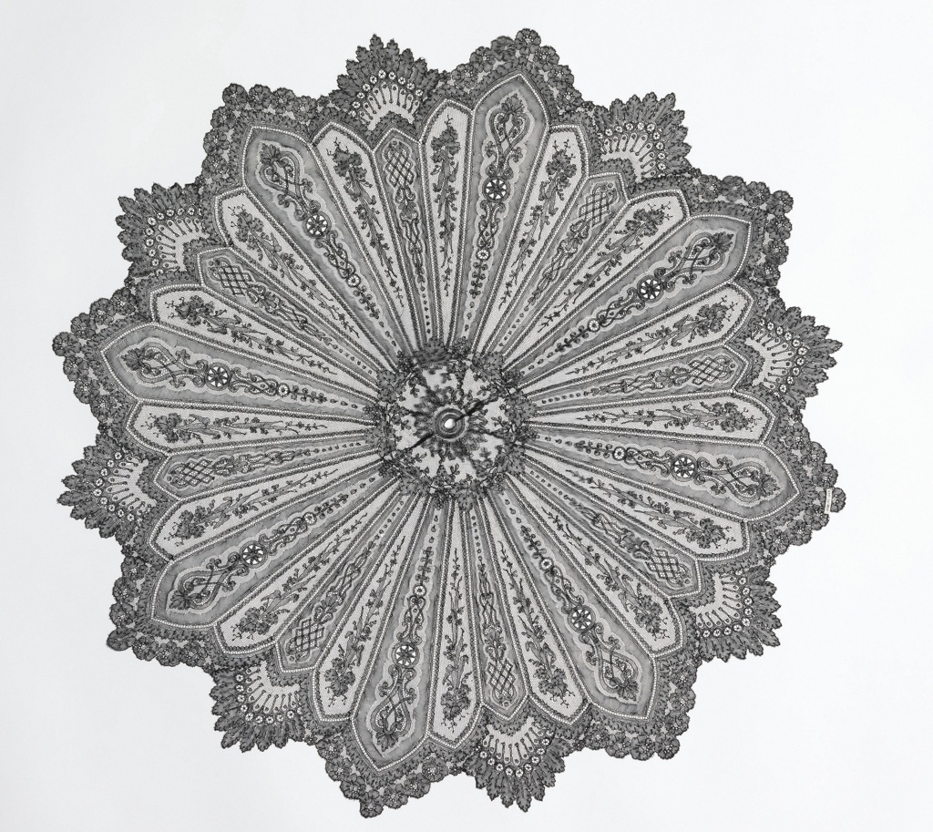 Black Chantilly lace parasol cover with a radiating floral design and deeply scalloped edge.
