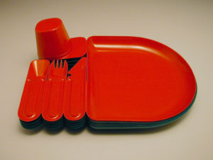 Image features a red plastic break-away tray, cup, spoon, knife, and fork molded as a single unit. The red tray-utensil combination is stacked on three green ones. Please scroll down to read the blog post about this object.