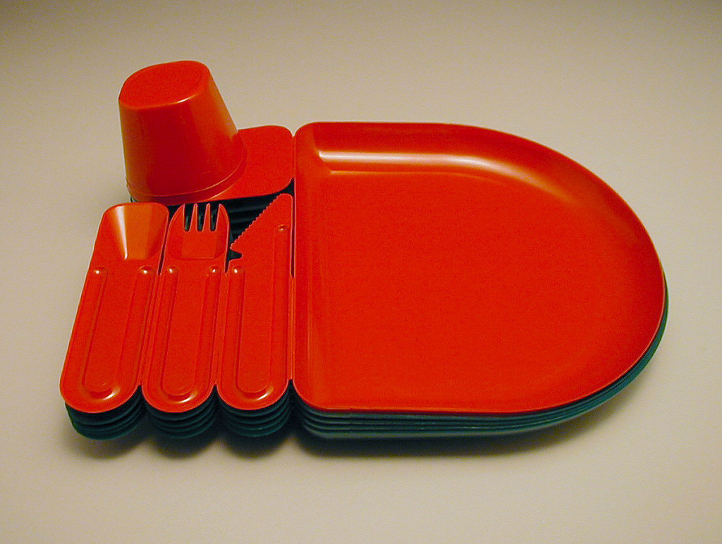 Image features a red plastic break-away tray, cup, spoon, knife, and fork molded as a single unit. The red tray-utensil combination is stacked on three green ones. Please scroll down to read the blog post about this object.