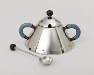Image features conical polished stainless steel sugar bowl with two blue plastic C-form handles accented with red beads, and a domed lid with black plastic knob. The bowl is accompanied by a simple hemispherical spoon on thin shaft terminating in a black plastic ball. Please scroll down to read the blog post about this object.