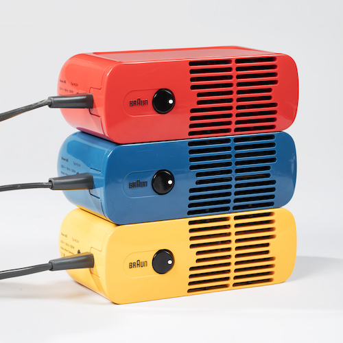 Three rounded, rectangular, plastic boxes stacked on a white background, each with vents, a black cord, and a black button. One red, one blue, and one yellow