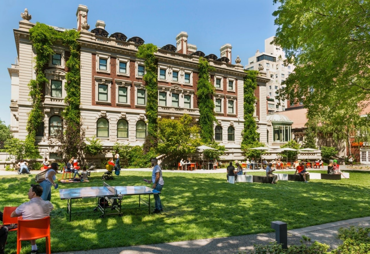 Exterior shot of Cooper Hewitt, with people interacting and playing in the garden