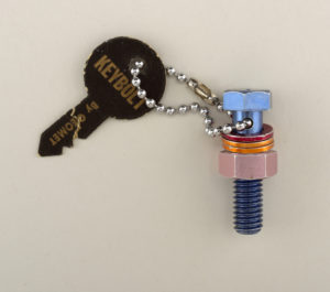 Image features key chain made from assembled blue anodized aluminum bolt, red and gold anodized aluminum washers, and violet anodized aluminum nut. Please scroll down to read the blog post about this object.