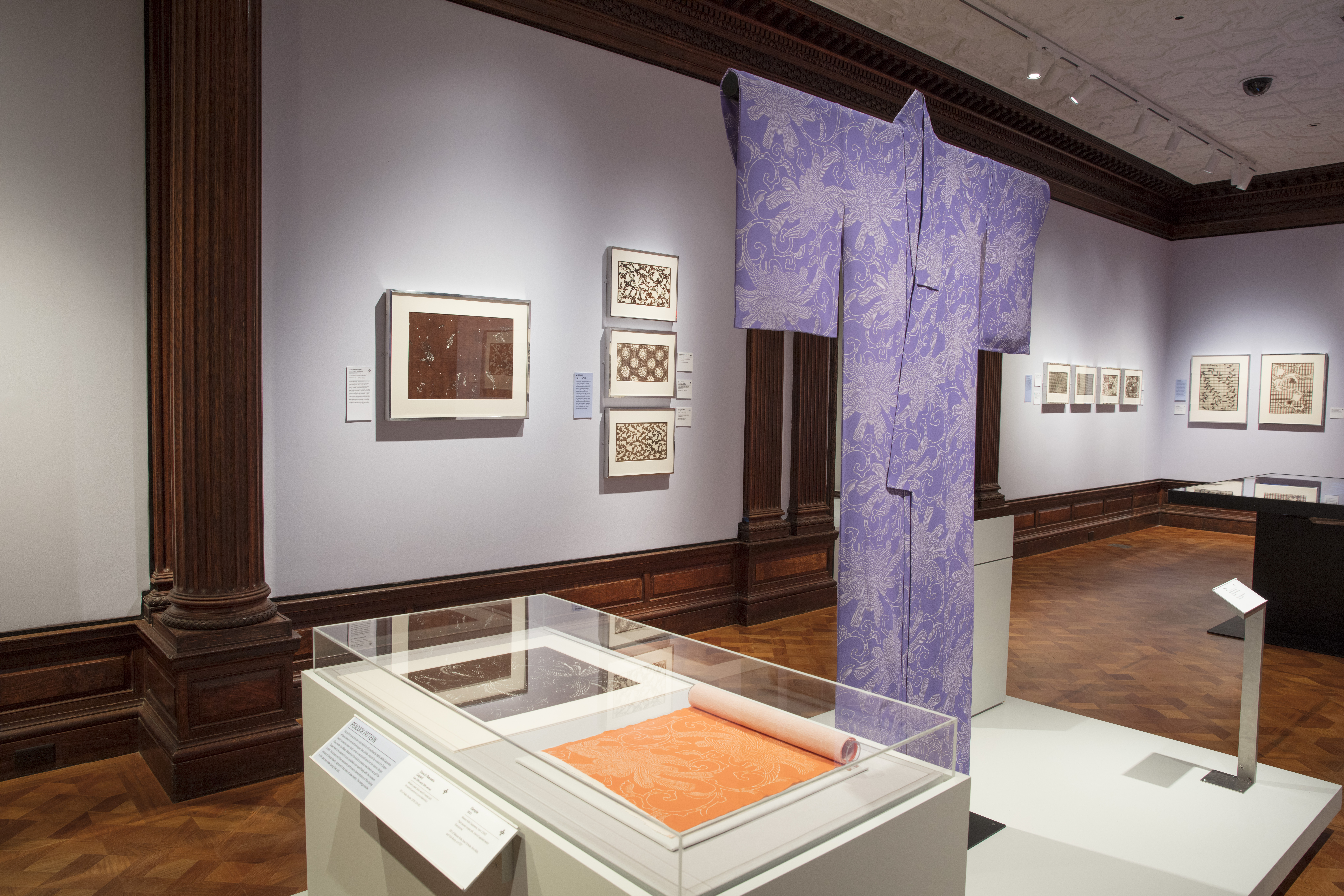 In the galleries of Cooper Hewitt, a blue kimono with a white design of what looks like flowers made of feathers is presented, hanging in a "T" form. In a case nearby, a orange version of the feather-flower design is displayed.