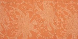 An orange fabric with an intricate white stenciled design of birds