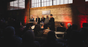 Image of a panel discussion with a brick wall behind the panelists.