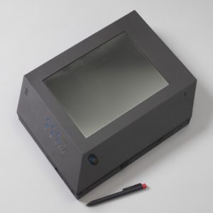 Image features tablet computer prototype in the form of a dark gray trapezoidal housing containing a rectangular screen; function buttons along the edges of the housing, and a separate pen-like gray stylus with red top. Please scroll down to read the blog post about this object.