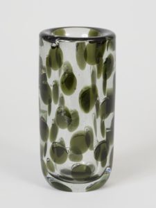 Image features a cylindrical vase of thick-walled clear glass with internal decoration of small translucent green discs, many topped by a small air bubble. Please scroll down to read the blog post about this object.