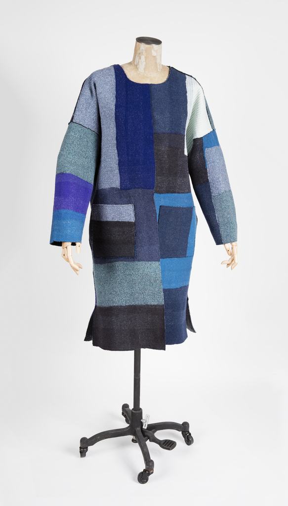 Image features: Long-sleeved, knee-length, reversible coat in needle-punched felt made from recycled sweaters. One side is a dark irregular plaid of blacks and blues, the other a patchwork of blue-tone knit fabrics. Please scroll down to read the blog post about this object.