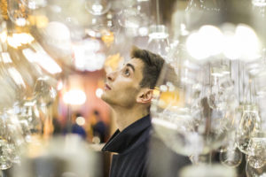 A man stares at wonder at the Curiosity Cloud, an installation composed of oversized incandescent lightbulbs suspended from the ceiling