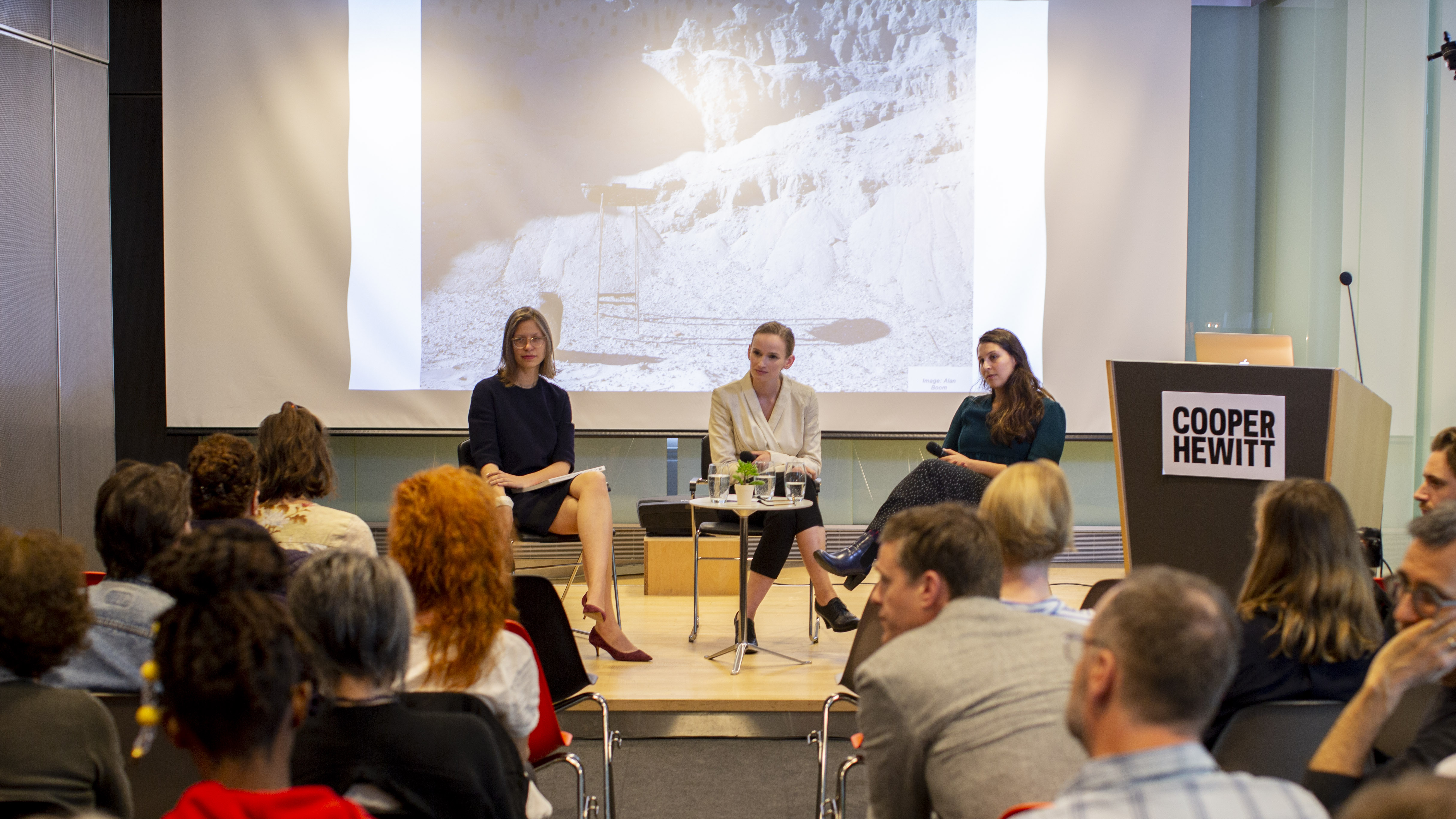Image from a panel discussion at Cooper Hewitt. Three women sit on a stage, holding microphones.