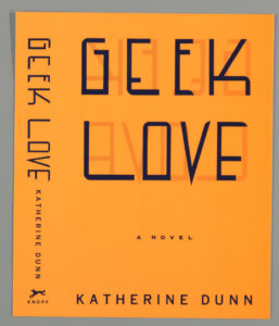 Image features a light orange book cover showing the title, GEEK LOVE, in black hand-lettered capital letters at top, the words overlapping their mirrored images in dark orange. Printed below the title, in black capital letters: A NOVEL / KATHERINE DUNN. At the left edge, hand-lettered text repeats the title and author's name on the spine. Please scroll down to read the blog post about this object.