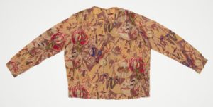 Image features a blouse with a round neckline and stitched pleats on either shoulder. Three snap closures on left proper shoulder. Long sleeved with banded cuff and snap closure. At the waist, belt loops are sewn on the seam. Please scroll down to read the blog post about this object.