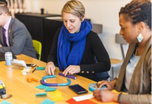 Educators sit a table prototyping using post-it notes and found materials